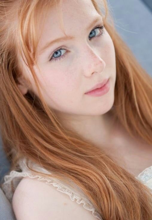 Strawberry blonde hair very long with bangs, Thick eyebrows, ice blue eyes,...